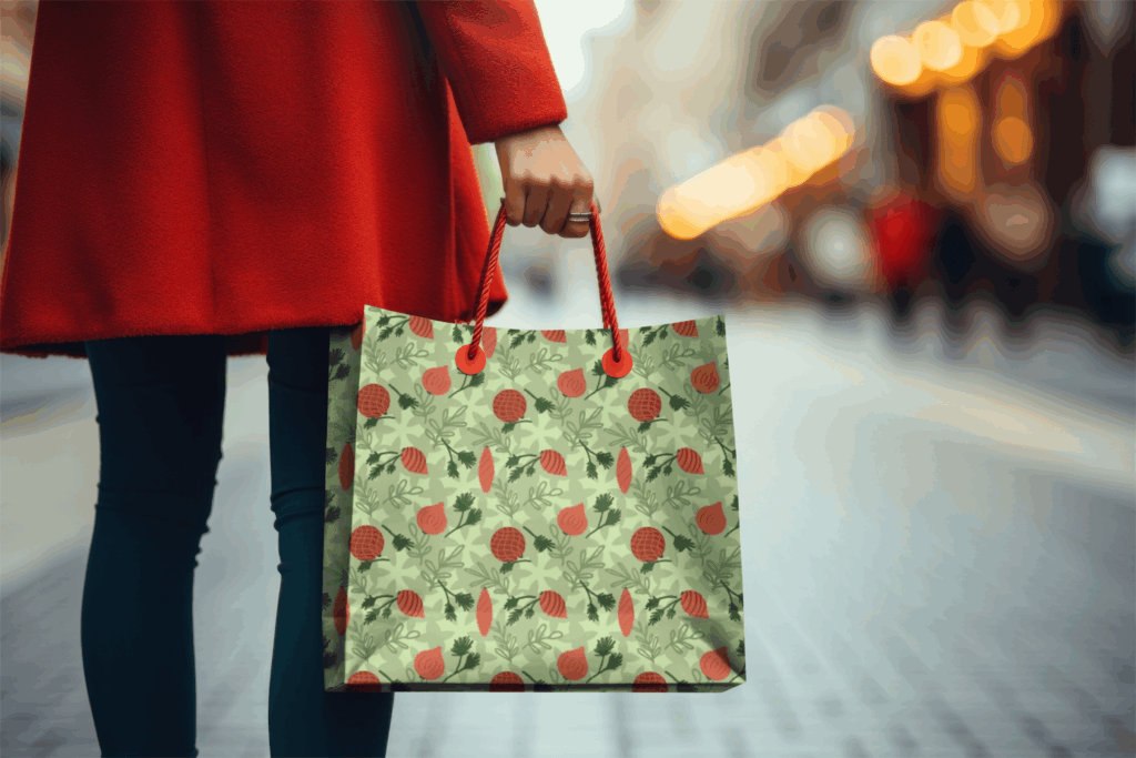 Person holding green gift bag with red pattern