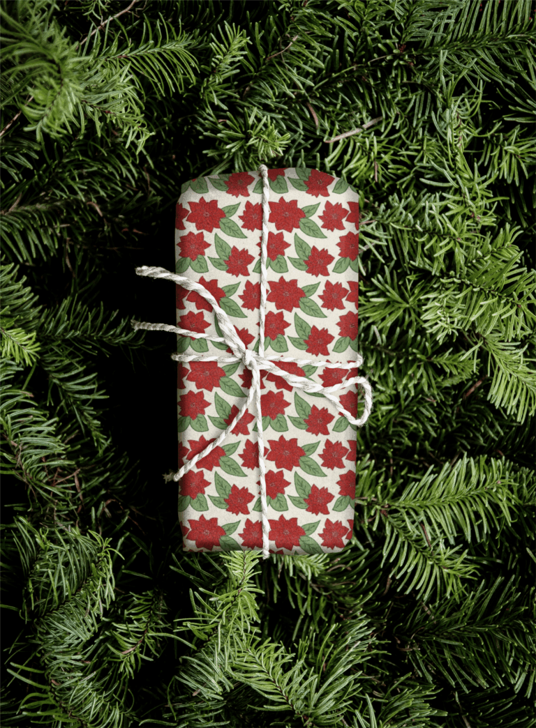 Wrapped gift with red floral pattern on greenery